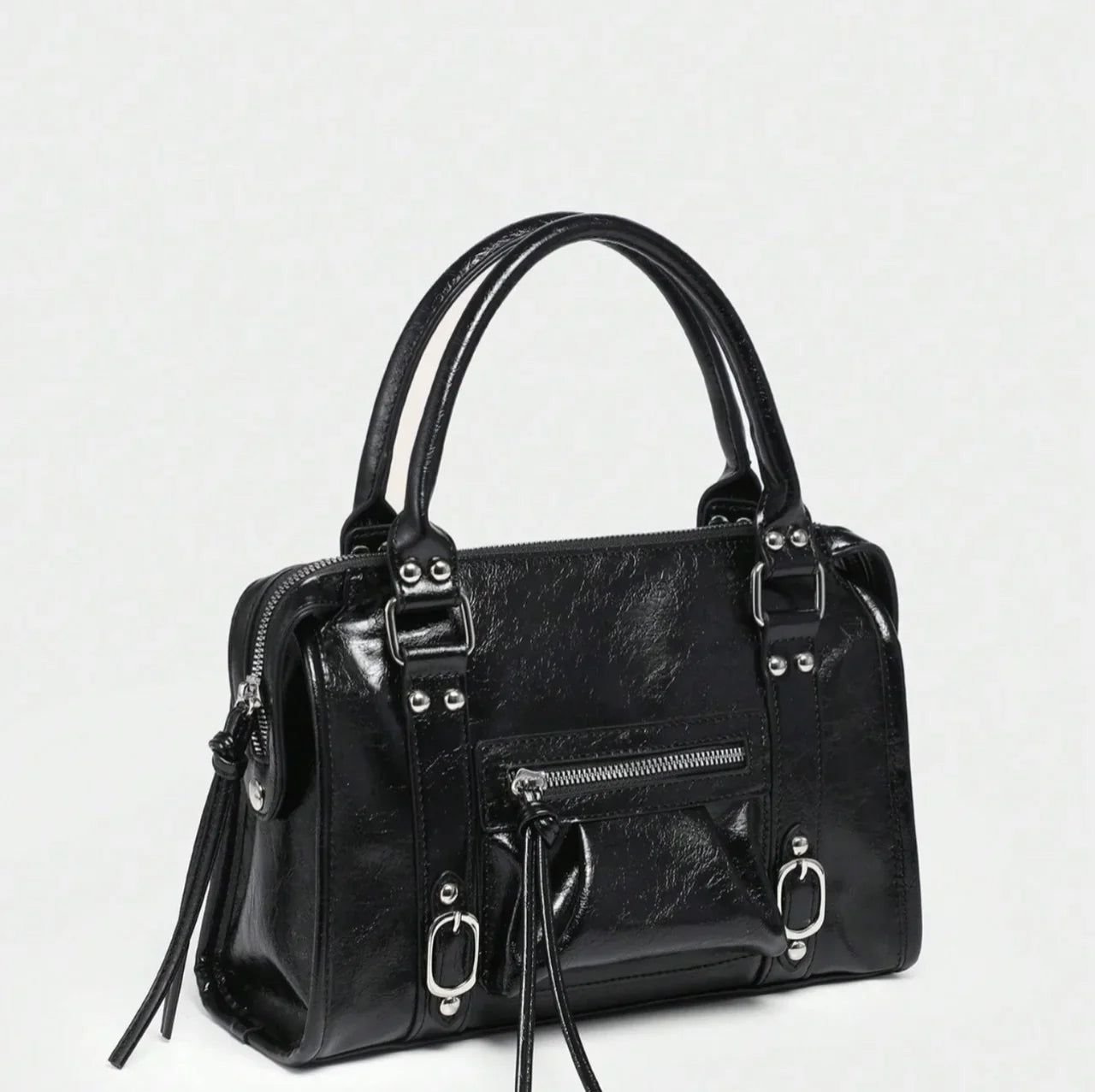 Sac à main CARLA en cuir noir effet brillant, avec détails métalliques, finitions soignées, anses solides, bandoulière réglable et grand compartiment zippé, parfait pour le travail et les sorties; vue de coté.