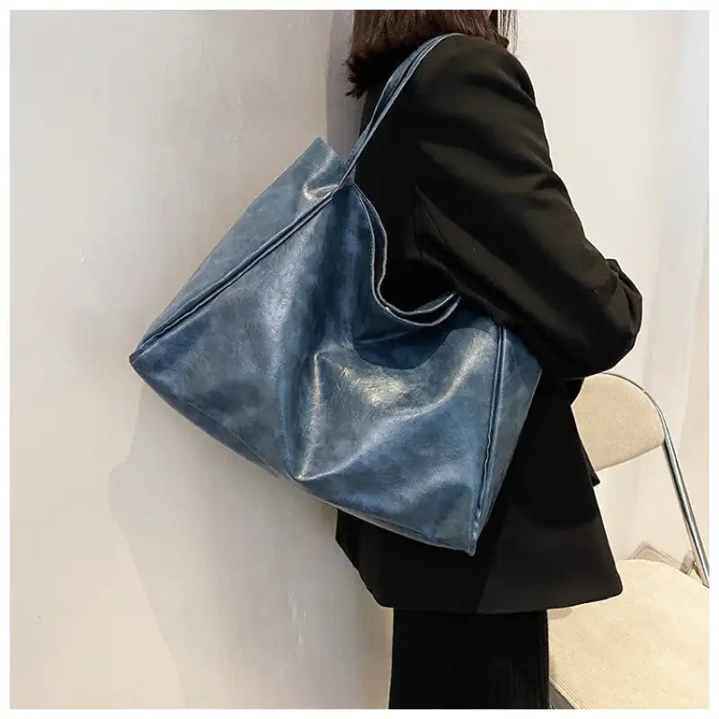 Sac à main LORIA en cuir bleu, moderne et chic, avec bandoulière ajustable, intérieur spacieux et compartiments organisés, parfait pour le quotidien et les sorties, porté épaule.