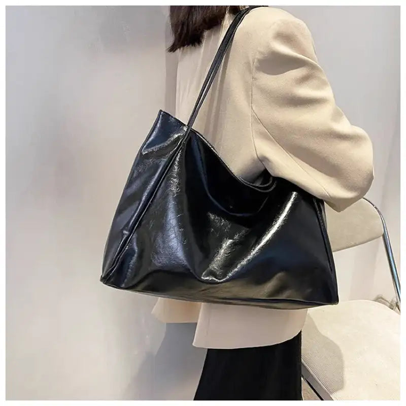 Sac à main LORIA en cuir noir, moderne et chic, avec bandoulière ajustable, intérieur spacieux et compartiments organisés, parfait pour le quotidien et les sorties, porté épaule.